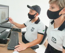 Policiais civis analisam digitais em tela de monitor
