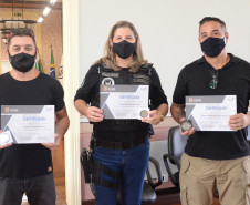 Três ganhadores do concurso posam para foto mostrando certificados e medalha