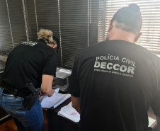 Dois policiais civis analisando documentos