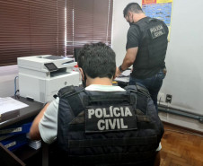 Dois policiais civis analisando documentos