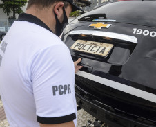 Policial civil fechando tampa de porta-malas de viatura