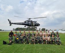 Participantes do treinamento posando para foto, tendo ao fundo o helicóptero