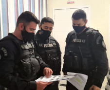 Três policiais civis verificando documentos