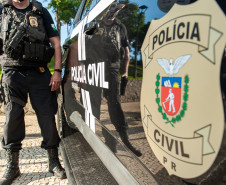 Policial civil ao lado de viatura