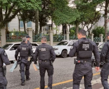 Seis policiais civis de costas, atravessando a rua