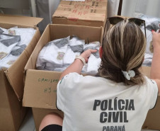 Policial civil verificando uniformes em diversas caixas abertas