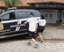 Dois policiais civis entrando em viatura