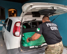 Policial civil recolhendo material do interior de veiculo