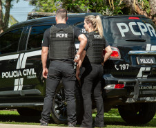Dois policiais ao lado de viatura