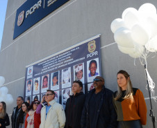 Policiais civis reunidos para fotografia. Ao fundo, banner com imagem dos desaparecidos