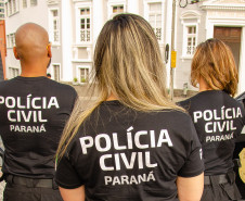 Três policiais civis de costas observando o movimento nas ruas