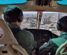 Pilotos em helicóptero sobrevoando a cidade