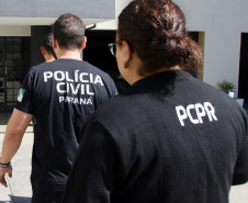 Três policiais civis entrando em delegacia