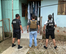 Três policiais em frente a residencia