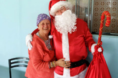 Senhora sorrindo abraçada no papai noel