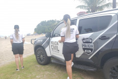 policiais civis perto de viatura na beira da praia 