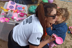 Criança dá um beijo no rosto de uma policial civil, em meio aos brinquedos