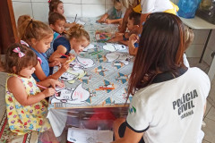 Policial civil orienta diversas crianças a colorir desenhos