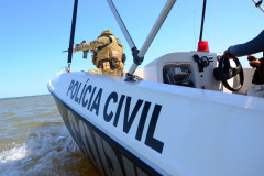 Policial civil empunhando fuzis em barco da corporação