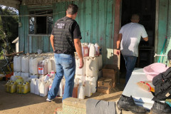 Policial civil adentrando em casa com produtos agrícolas recuperados