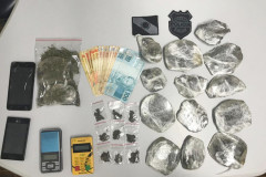 Drogas, máquina de cartão, celulares e dinheiro sobre uma mesa