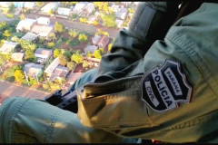 Policial civil do Grupo de Operações Aéreas em voo de helicoptero observando a região