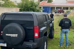 Policiais civis ao lado de veículo apreendido