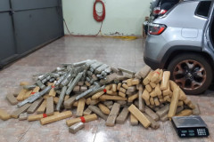 Diversos tabletes de droga e uma balança, ao lado de veículo