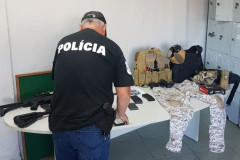 Policial civil organizando sobre uma mesa o material apreendido