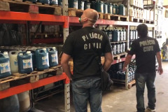 Policiais observam prateleiras cheias de galões de álcool etílico
