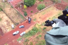 Policial civil em helicóptero acompanhando operação de policiais em terra