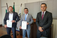 Delegado-geral e superintendente da CGU apresentando documento assinado. Junto, chefe da divisão de combate à corrupção.