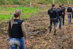 Policiais civis caminhando por uma área rural