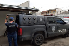 Policial civil segurando tampa de porta-malas de viatura 