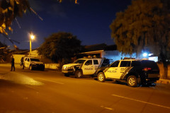 Três viaturas da polícia civil estacionadas e um policial andando