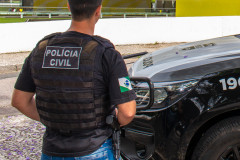 Policial civil ao lado de viatura