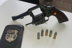 Arma, munições e carteira da polícia sobre uma mesa