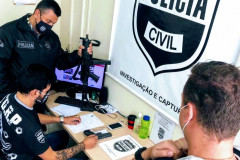 Policiais em uma mesa, averiguando material apreendido