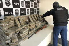 Policial civil empilhando tabletes de droga, sobre uma mesa