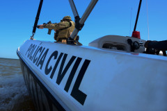 No interior de um barco da polícia civil, policial aponta arma
