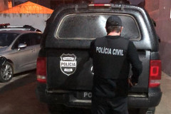 Policial civil de costas, ao lado de viatura