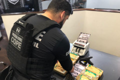 Policial civil organiza material apreendido, sobre uma mesa