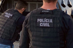 Dois policiais civis ao lado de viatura
