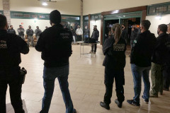 Policiais civis enfileirados, de costas