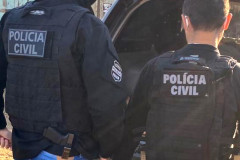 Dois policiais civis ao lado de viatura