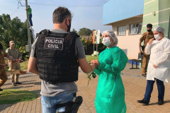Policial civil entregando uma flor a uma profissional da saúde