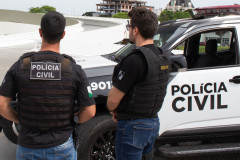 Policiais civis ao lado de viatura