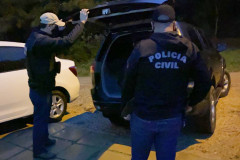 Policiais civis ao lado de viatura