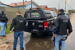 Policiais civis ao lado de viatura