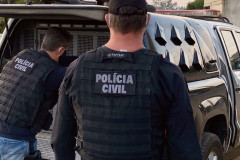 Policiais civis ao lado de viatura